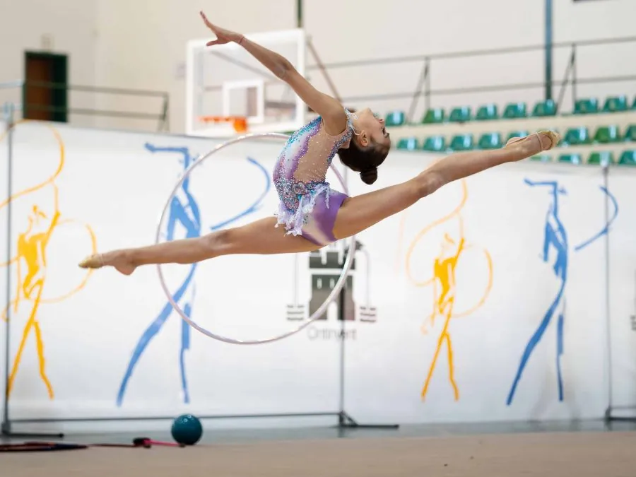 Gimnasta de rítmica en pleno salto con aro durante una competición autonómica en Ontinyent.